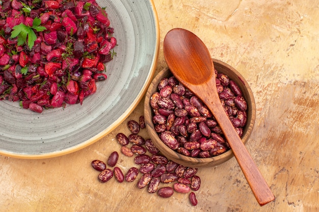 Free photo above view of delicious salad with beetroot and bean and beans inside and outside of pot on mixed color background