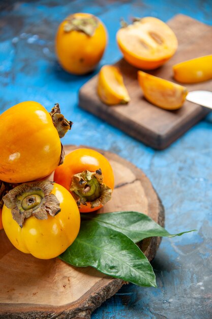 Above view of delicious whole and cut diospyros kaki on brown wooden cutting board