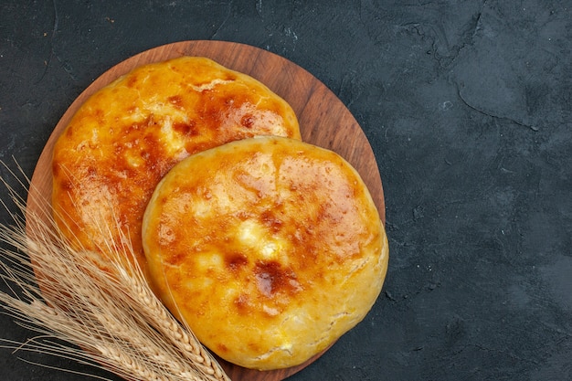 Above view of delicous fresh baked pastries and spike on the wooden cutting board on dark blackground