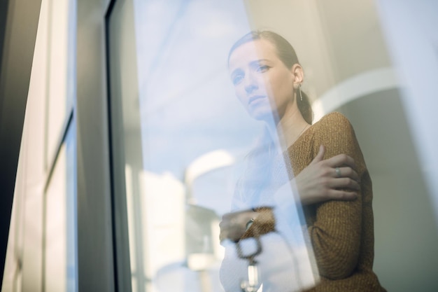 Below view of depressed woman looking through the window