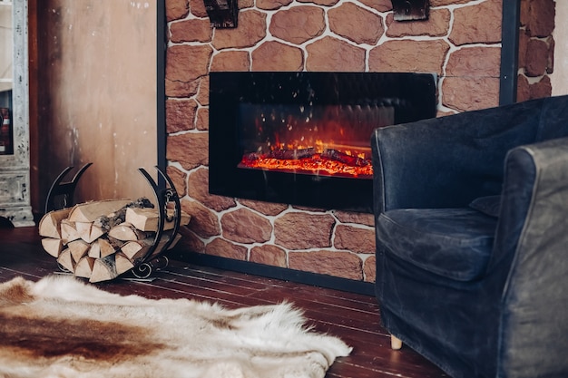 Free photo view over fireplace with burning logs, natural fur skin on the floor next to holder with logs in cozy room.