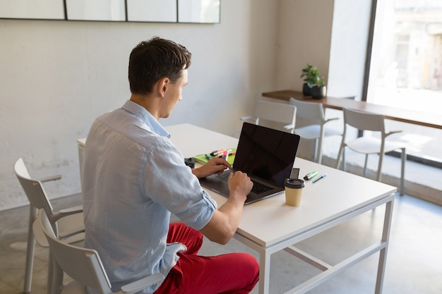 View from back on young man working in co-working office room