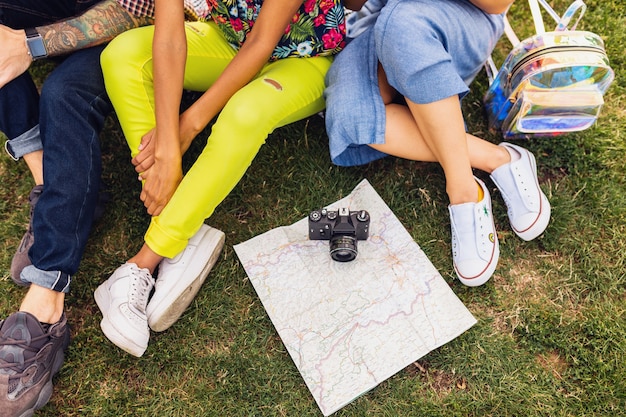 View from above of legs and shoes of young company of friends sitting park, man and women having fun together