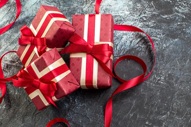 Above view of gifts in beautifully packaged boxes tied with satin ribbon for beloved one on the right side on dark table