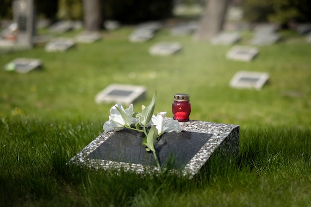 Free photo view of gravestone with flowers and candle