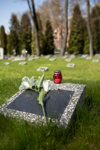 Free photo view of gravestone with flowers and candle