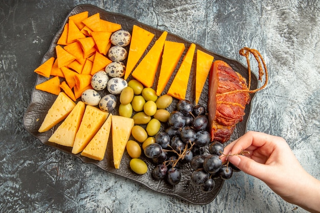 Free photo above view of hand taking one of foods from delicious best snack for wine on brown tray on ice background