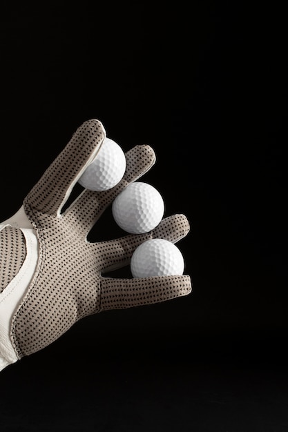 View of hand with glove holding golf balls