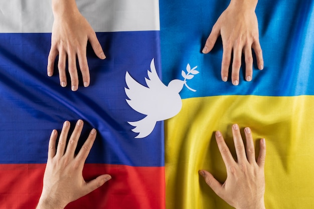 Free photo above view hands on ukrainian and russian flags