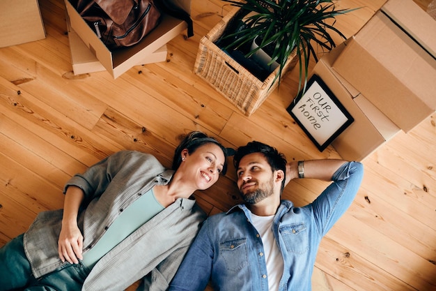 Above view of happy couple relaxing on the floor after buying their first home