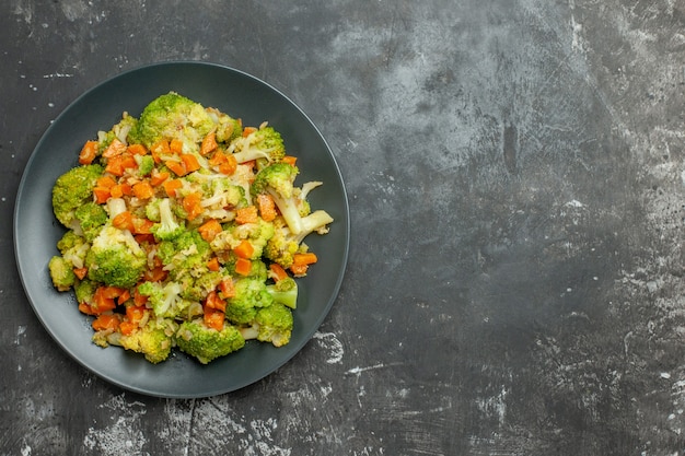 Free photo above view of healthy meal with brocoli and carrots on a black plate on gray table