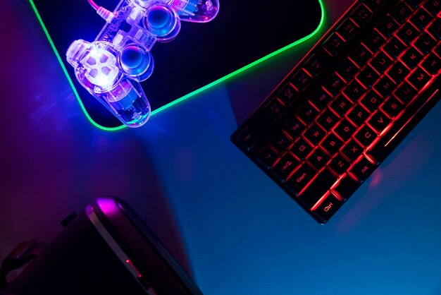 View of illuminated neon gaming keyboard setup and controller