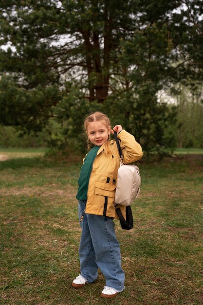 View of little girl with backpack adventuring in nature