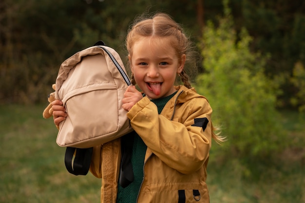 View of little girl with backpack adventuring in nature