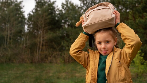 View of little girl with backpack adventuring in nature