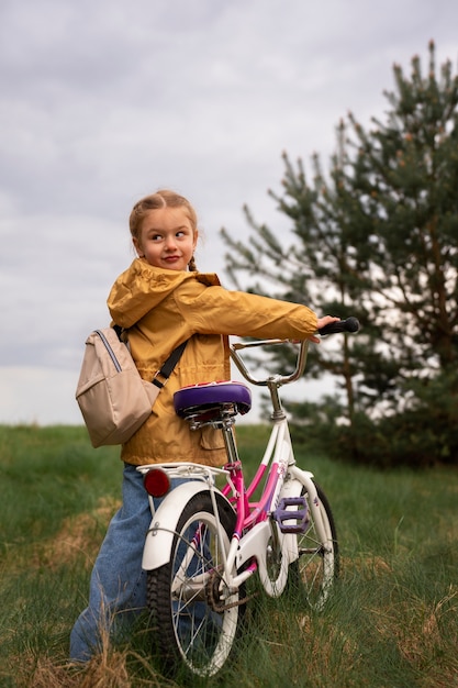 View of little girl with backpack and bike adventuring in nature