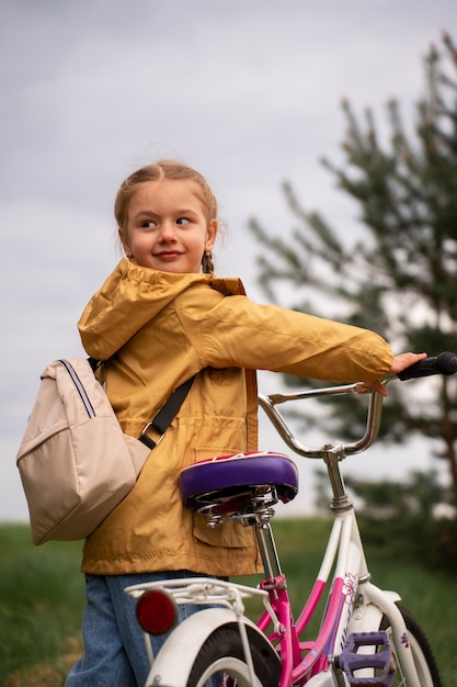 View of little girl with backpack and bike adventuring in nature