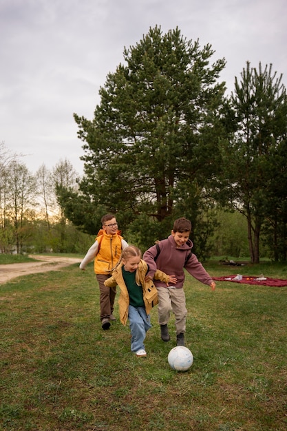 View of little kids with backpacks playing ball in nature