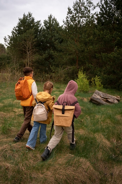 Free photo view of little kids with backpacks spending time in nature outdoors