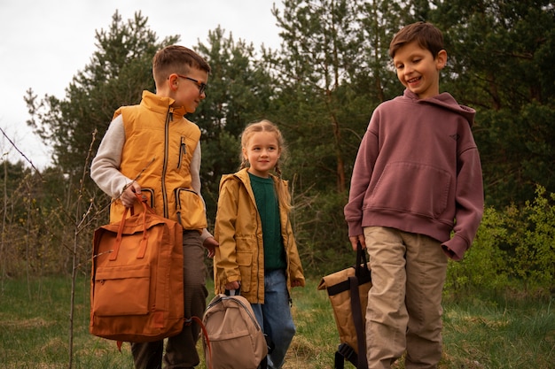 Free photo view of little kids with backpacks spending time in nature outdoors