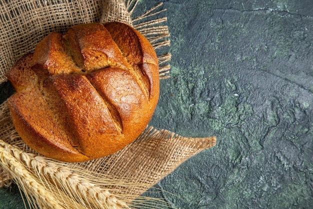 Above view of a loaf of dietary black bread on brown towel on dark colors surface