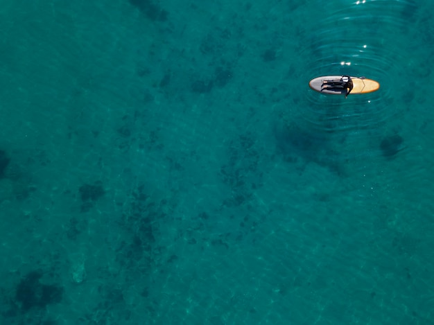 Free photo above view man laying on surfboard