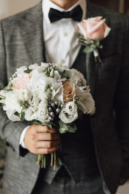 View of a man's chest dressed in stylish grey suit with wedding bouquet and boutonniere