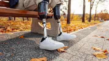 Free photo view of a man with prosthetic legs and white sneakers sitting on a bench in a park