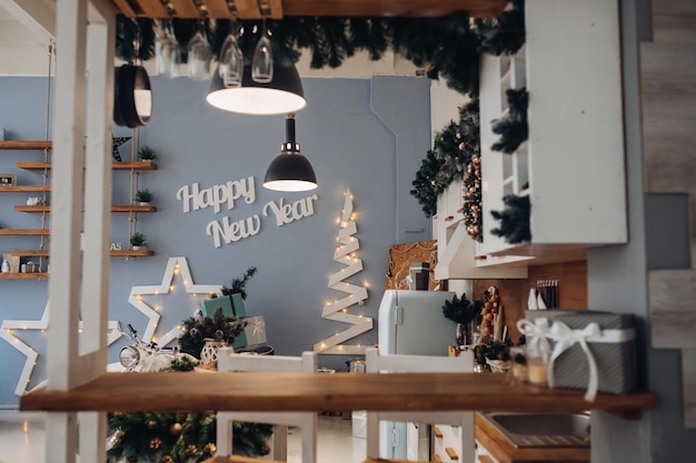 View over modern kitchen decorated for Christmas with decorative stars, objects and decorative Christmas tree with Christmas presents.