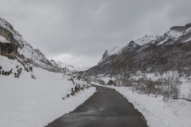 View a narrow road with high mountains covered with snow on both sides