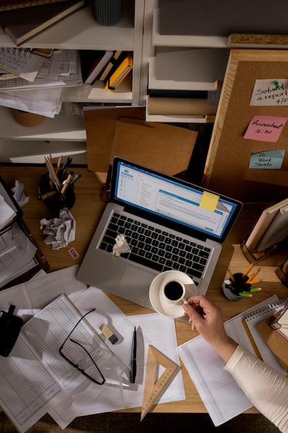 Free Photo view of office desk with messy workspace and laptop