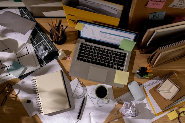 Free Photo view of office desk with messy workspace and laptop