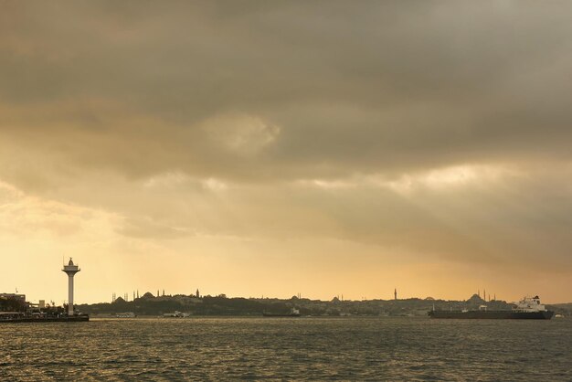 View of the old historical building with mosques towers buildings in the eastern style cargo ships tugboats in the port on the roadstead on the background of cloudy sky