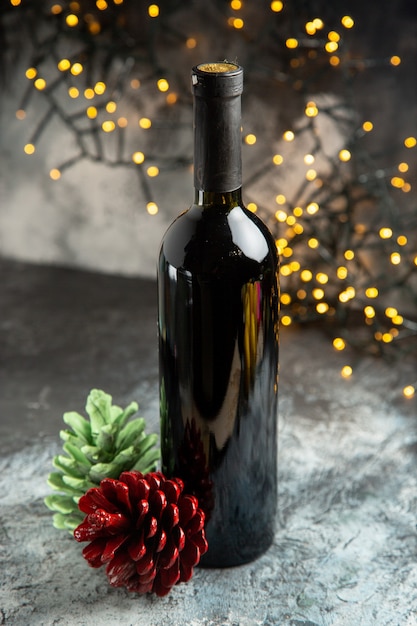 Above view of red wine bottle for celebration and two conifer cones on dark background