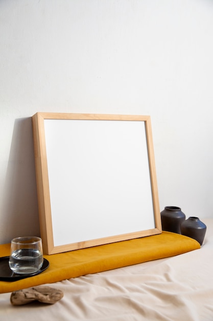 Free photo view of room decor made up of frame and glass of water with vases