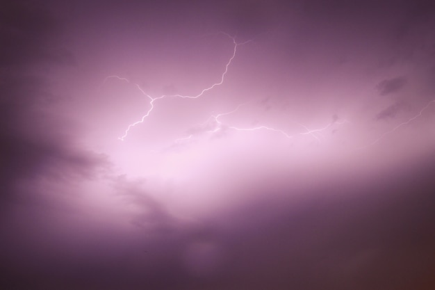 View of the sky capturing a bolt of lightning with purple cloudy skies