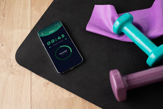 View of smartphone with weights and yoga mat