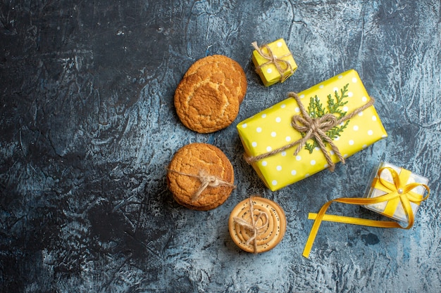 Above view of stacked beautiful yellow Christmas gift boxes and various cookies on dark background