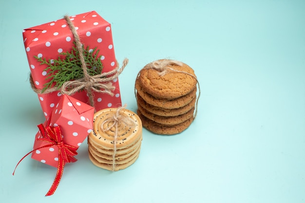 Free photo above view of stacked various delicious cookies red gift boxes on pastel green background