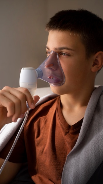 Free photo view of teenage boy using nebulizer at home for respiratory health problems