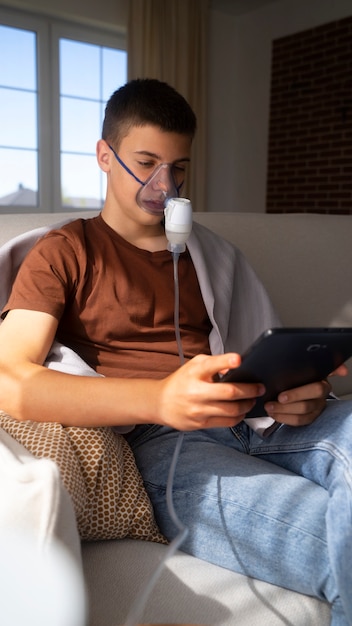 Free photo view of teenage boy using nebulizer at home for respiratory health problems