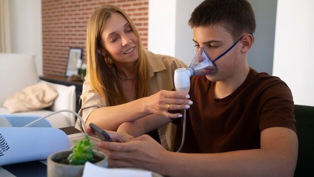 View of teenage boy using nebulizer at home for respiratory health problems