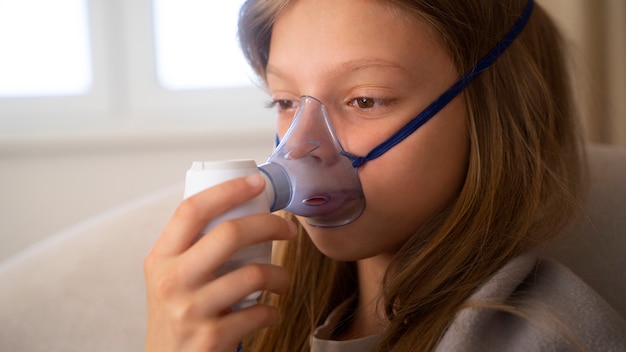 Free photo view of teenage girl using nebulizer at home for respiratory health problems