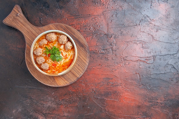 Free Photo above view of tomato meatballs soup with noodles in a brown bowl on dark background