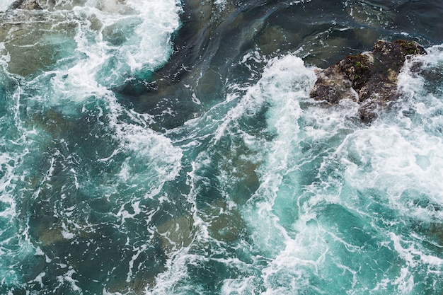 Above view wavy water at rocky shore