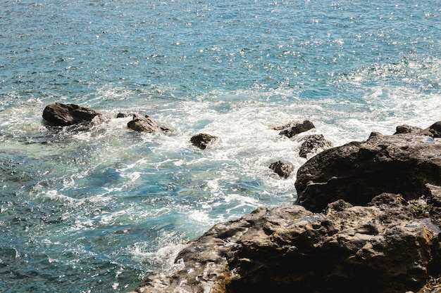 Above view wavy water at rocky shore