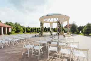 Free photo view of white guest chairs and decorated ceremonial archway open air on the sunny day