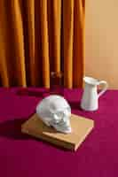 Free photo view of white skull with book and vase