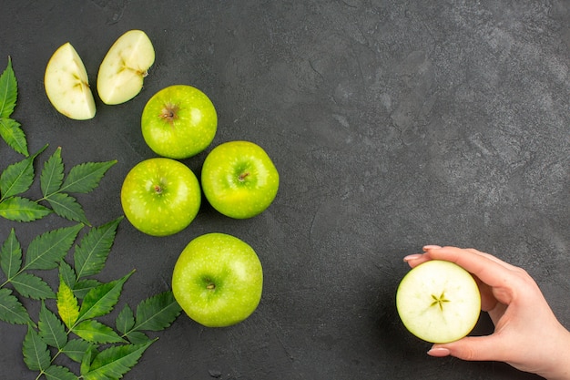 Above view of whole and chopped fresh green apples and mint on black background