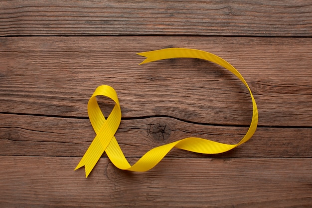 Free Photo view of yellow ribbon on wooden background